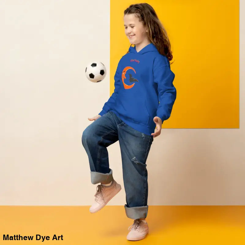 Girl in blue Bat Baby hoodie playing with a soccer ball in a spooky setting