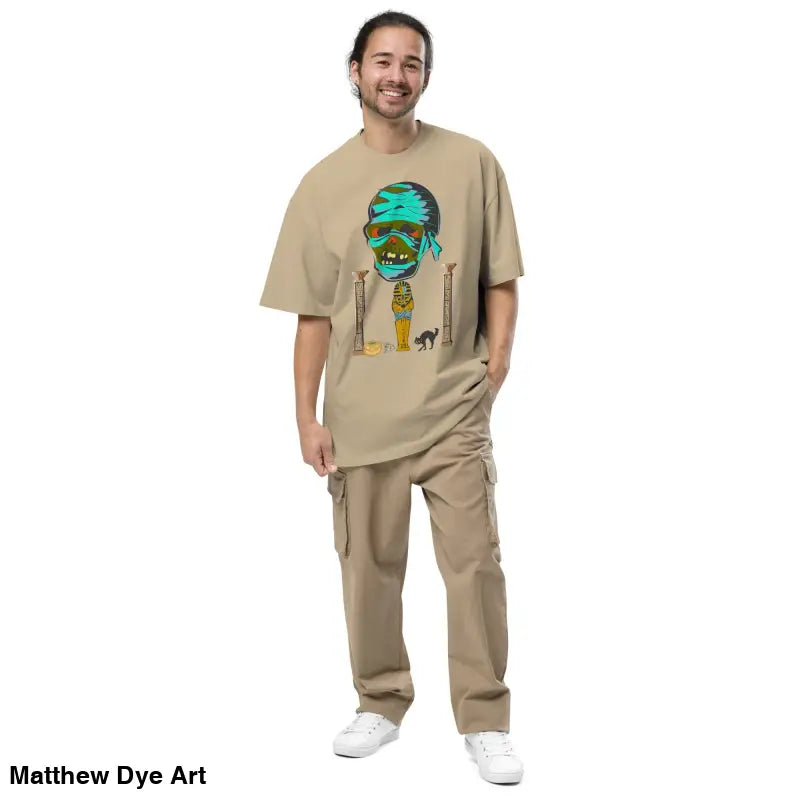 Man models Pharaoh’s Curse oversized tee featuring a mummy graphic in tan outfit