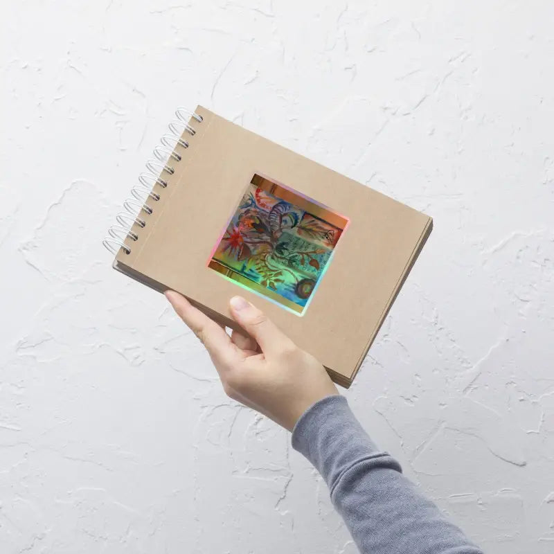 Hand holding a spiral notebook featuring Voynich Kiss-Cut Holographic Stickers artwork