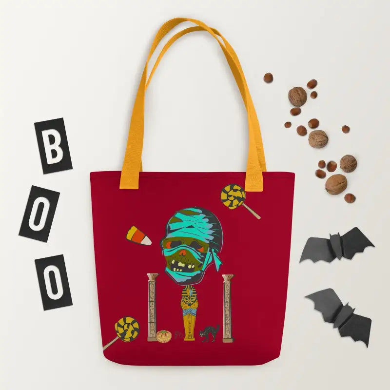 Red reusable trick or treat tote bag with yellow handles featuring a Halloween mummy design