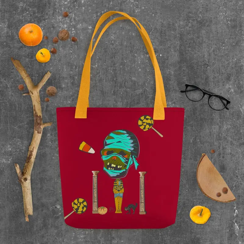 Burgundy reusable trick or treat tote bag featuring a quirky mummy design with yellow straps