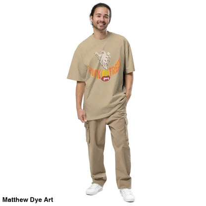 Man in beige outfit wearing oversized faded t-shirt with vampire fangs design