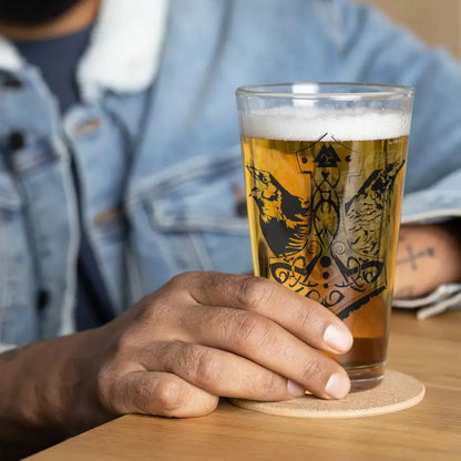 Golden beer in a Raven Design shaker pint glass featuring decorative artwork