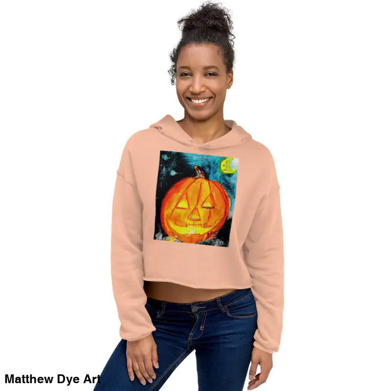 Peach-colored cropped hoodie featuring a spooky cute jack-o’-lantern design by Matthew Dye Art