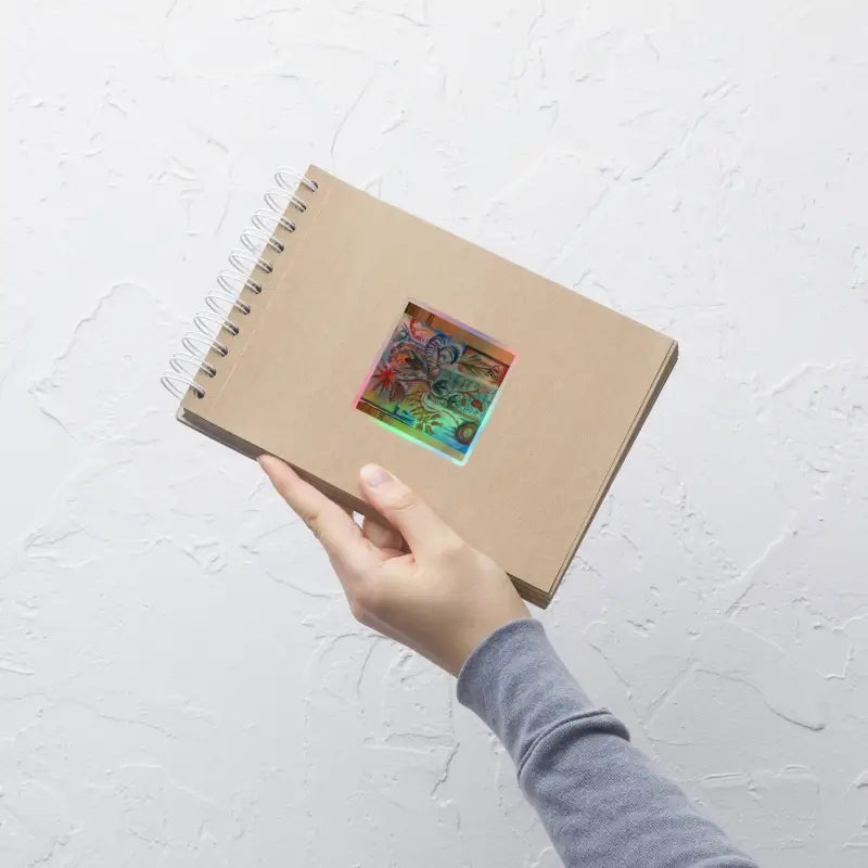 Hand holding a spiral-bound notebook with Voynich Kiss-Cut Holographic Stickers displayed