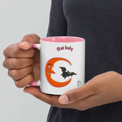 White coffee mug with pink rim featuring smiling orange crescent and black bat silhouette