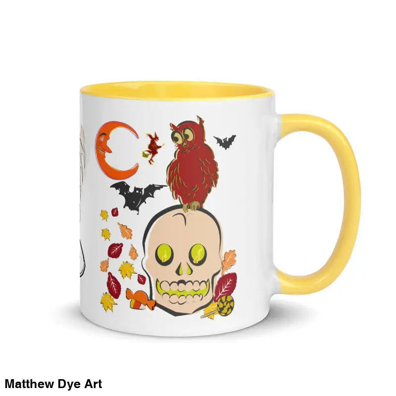 White ceramic mug with yellow handle featuring Halloween skull, owl, bats, and leaves